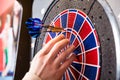 Person`s hand removing arrows from dartboard