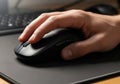 A person\'s hand resting on a black computer mouse, placed on a dark mouse pad. Th Royalty Free Stock Photo