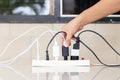 A person's hand unplugging a wire from an overloaded power strip with multiple plugs Royalty Free Stock Photo