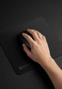 A person\'s hand using a black computer mouse on a matching black mouse pad. The surface appears Royalty Free Stock Photo