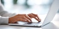 Close-up of hands typing on laptop keyboard in bright modern workspace with soft natural light and blurred background Royalty Free Stock Photo