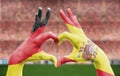 Person`s hands forming a heart with the flags of Germany and Spain - love towards football concept