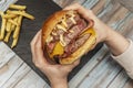 Person's hands holding a beastly three meat burger with lots Royalty Free Stock Photo