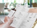 Person`s hands holding menu and mobile phone in restaurant. A foreign man in cafe ordering food using word translation program wh Royalty Free Stock Photo