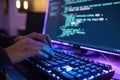Person s hands typing on a glowing keyboard in front of a computer screen displaying code Royalty Free Stock Photo