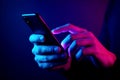 Person\'s hands using a smartphone illuminated by pink and blue neon lights mobile phone technology Royalty Free Stock Photo
