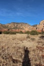 A person\'s shadow cast on a prairie like plateau on the Brins Mesa Trail lined by sandstone and limestone mountains Royalty Free Stock Photo