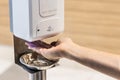 Person sanitizing hands with liquid gel from public sanitizing machine