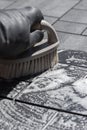 Person scrubbing composite decking tile patio with a hand brush.