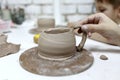 Person sculpts clay mug