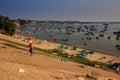 Person on Seafront Slope Boats on Beach in Sea at Sunset