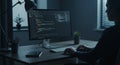 A person is seated at a desk working on a computer displaying code. The Royalty Free Stock Photo