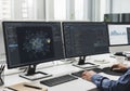 A person is seated at a desk working with dual monitors displaying a programming interface and data Royalty Free Stock Photo