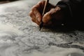 A person is seen writing on a piece of paper using a pen, A calligrapher creating intricate patterns, AI Generated