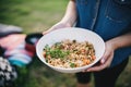 person serving farro salad from large bowl at picnic