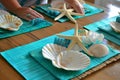 person setting a table with turquoise placemats, white starfish decorations, and shellshaped dishes