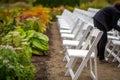 person setting up white chairs in a garden row