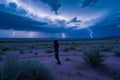 person shielding face, walking through desert lightning storm Royalty Free Stock Photo