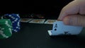 Person showing his deck at the poker game. Card player checks his hand, two aces in, chips in background on green Royalty Free Stock Photo