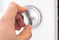 A person Shutting off a door with a round pocket door lock on a white door