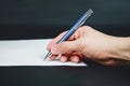 Person sign document and hand holds blue pen on dark background Royalty Free Stock Photo