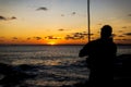 A person, in silhouette, playing the Berimbau against the sunset