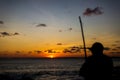 A person, in silhouette, playing the Berimbau against the sunset