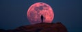 Person silhouetted against a giant full moon on a rocky hill at dusk Royalty Free Stock Photo