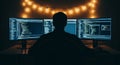 Silhouette of a person coding on multiple monitors in a dark room with string lights programmer computer Royalty Free Stock Photo