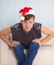 Person sits on sofa in a red Christmas cap Royalty Free Stock Photo