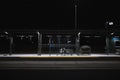 Person sitting alone at bus stop at night