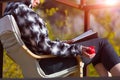 Person sitting in Chair inside rural Garden reading Book holding Pomegranate