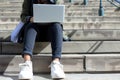 person sitting on courthouse steps, reviewing notes with a laptop