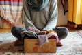 person sitting crosslegged on the floor with a box of scarves