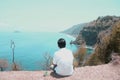 Person sitting on a cliff. A young man relax sitting alone on beach enjoying the sea view with a cup of coffee. Royalty Free Stock Photo