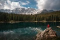 Person sitting by the Lake Carezza with Mount Latemar, Bolzano province, South Tyrol, Italy
