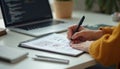 Person sketches ideas notepad, minimalistic workspace background. Laptop with code open. Designer, developer draws app interface, Royalty Free Stock Photo