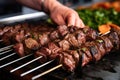 person skewering pieces of lamb for kebabs