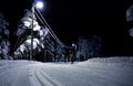 Person skiing in a cross country slope through an idyllic lit forest at night