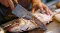 A person skillfully slicing through a fish with a sharp knife, preparing it for cooking or consumption