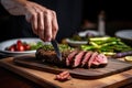 person slicing grilled seitan steak on a plate