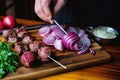 person slicing onions to serve with grilled lamb kebabs