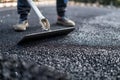 person smoothing asphalt with a hand tamper on pavement