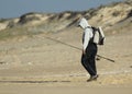 Person in a sports costume with a big backpack fishing in the seashore with blurred background