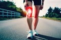 Person in sportswear depicts pain in the knee against the background of the road while walking in the countryside - Generative AI