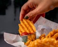 Person spreading ketchup on crunchy crisscut