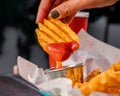 Person spreading ketchup on crunchy crisscut