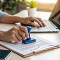 Person stamping document while typing on laptop Royalty Free Stock Photo