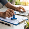 Person stamping document while typing on laptop computer Royalty Free Stock Photo
