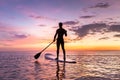 Person stand up paddle boarding, dusk, quiet sea, sunset colors